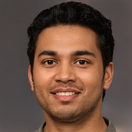 Joyful latino young-adult male with short  black hair and brown eyes