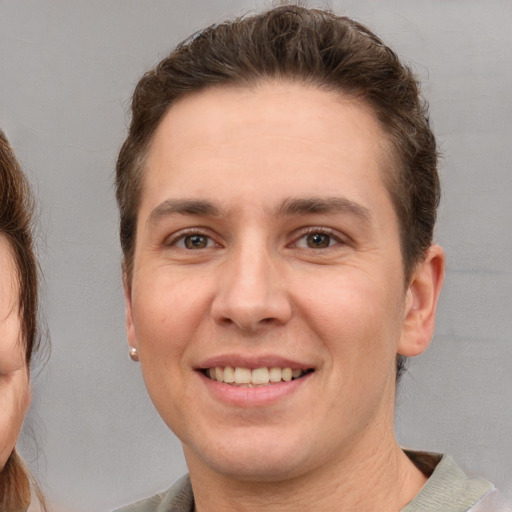 Joyful white young-adult male with short  brown hair and grey eyes