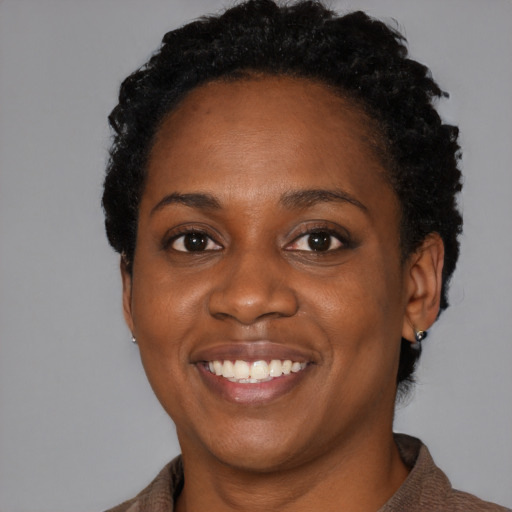 Joyful black young-adult female with short  black hair and brown eyes