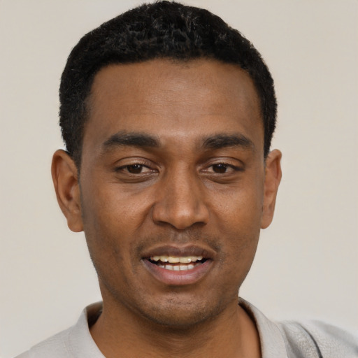 Joyful black young-adult male with short  black hair and brown eyes