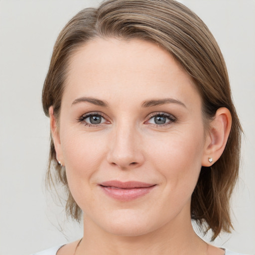 Joyful white young-adult female with medium  brown hair and grey eyes