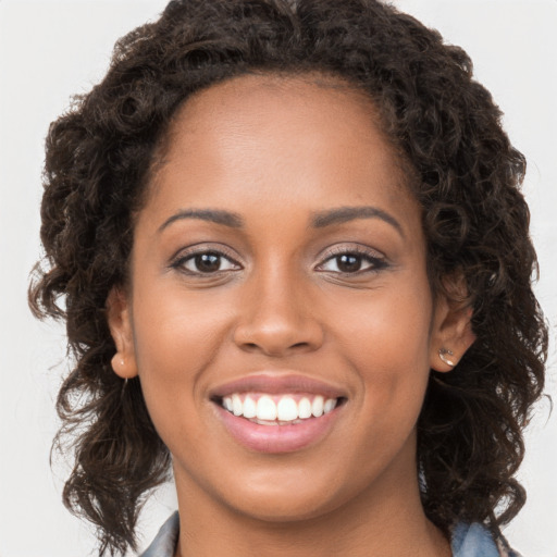 Joyful black young-adult female with long  brown hair and brown eyes