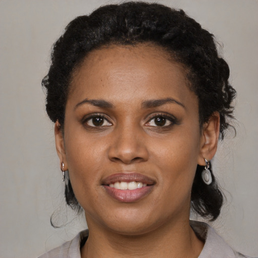 Joyful black young-adult female with long  black hair and brown eyes