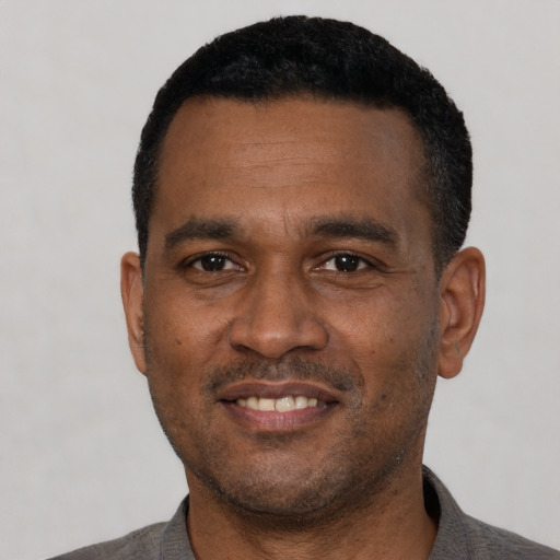 Joyful black adult male with short  black hair and brown eyes