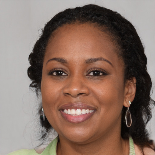 Joyful black young-adult female with long  brown hair and brown eyes