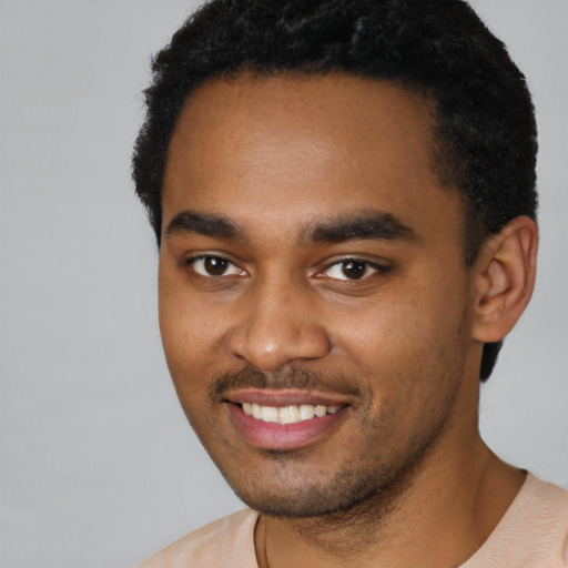 Joyful black young-adult male with short  black hair and brown eyes