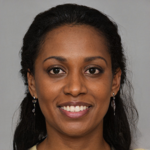 Joyful black young-adult female with long  brown hair and brown eyes