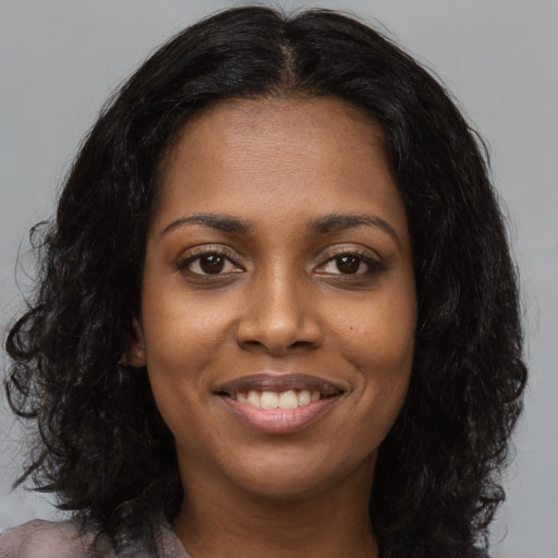 Joyful black young-adult female with long  brown hair and brown eyes