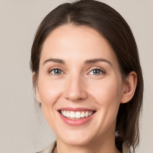 Joyful white young-adult female with medium  brown hair and grey eyes