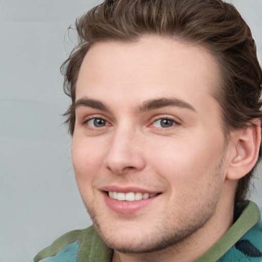 Joyful white young-adult male with short  brown hair and blue eyes