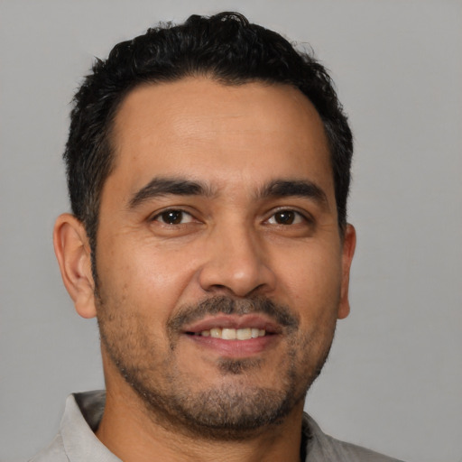 Joyful latino young-adult male with short  black hair and brown eyes