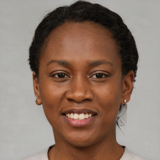 Joyful black young-adult female with short  black hair and brown eyes