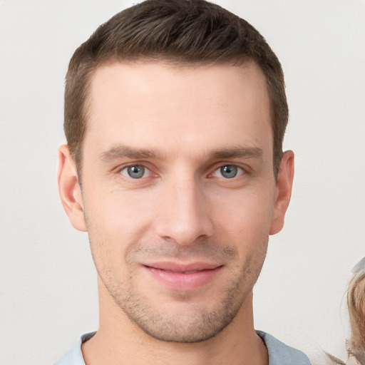 Joyful white young-adult male with short  brown hair and grey eyes