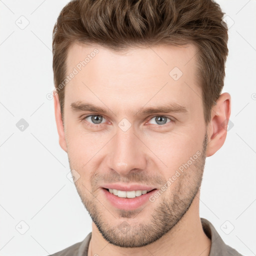 Joyful white young-adult male with short  brown hair and grey eyes