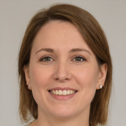 Joyful white young-adult female with medium  brown hair and grey eyes