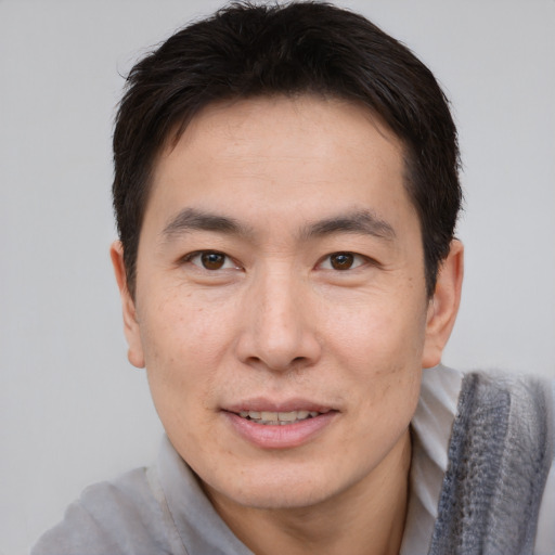Joyful asian adult male with short  brown hair and brown eyes