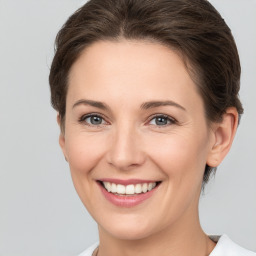 Joyful white young-adult female with medium  brown hair and grey eyes