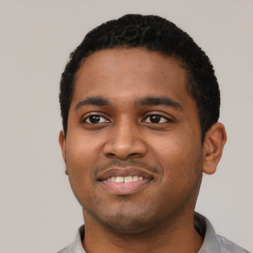 Joyful black young-adult male with short  black hair and brown eyes