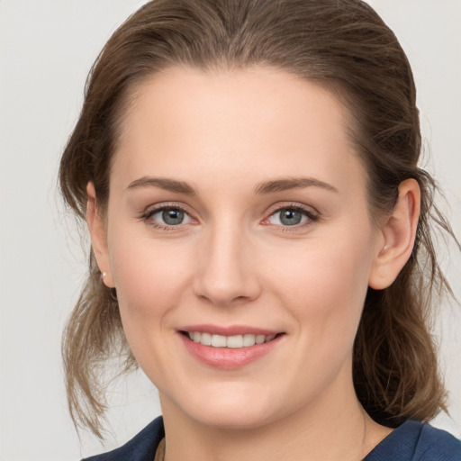 Joyful white young-adult female with medium  brown hair and grey eyes