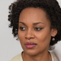 Joyful black young-adult female with long  brown hair and brown eyes