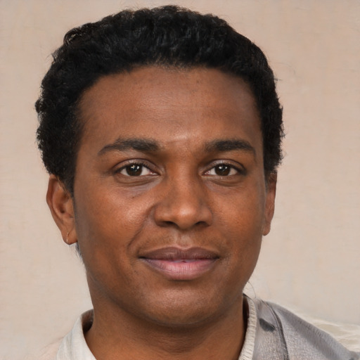 Joyful black young-adult male with short  brown hair and brown eyes