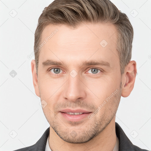 Joyful white young-adult male with short  brown hair and grey eyes