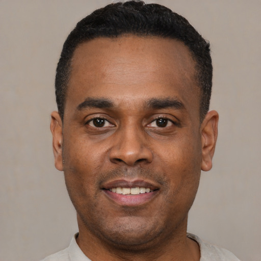 Joyful black young-adult male with short  black hair and brown eyes