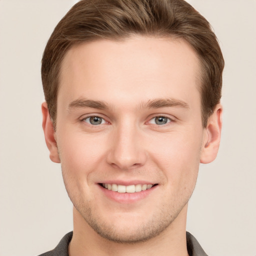 Joyful white young-adult male with short  brown hair and grey eyes