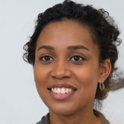 Joyful black young-adult female with long  brown hair and brown eyes