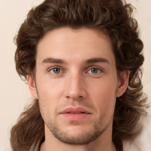 Joyful white young-adult male with long  brown hair and brown eyes