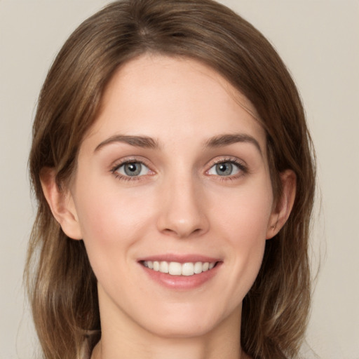 Joyful white young-adult female with medium  brown hair and grey eyes