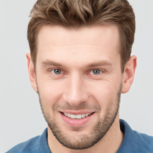 Joyful white young-adult male with short  brown hair and grey eyes