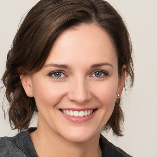 Joyful white young-adult female with medium  brown hair and grey eyes