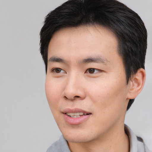 Joyful asian young-adult male with short  brown hair and brown eyes