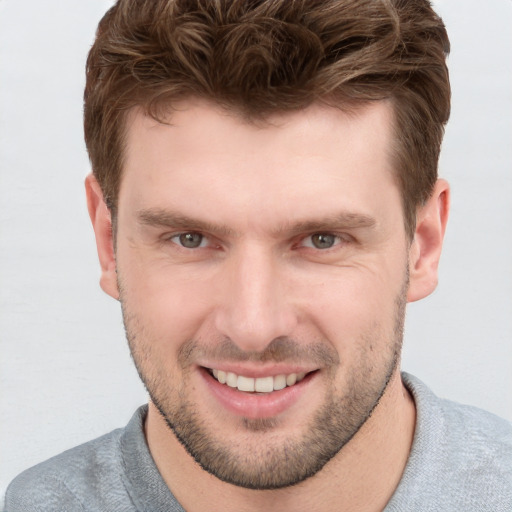 Joyful white young-adult male with short  brown hair and grey eyes