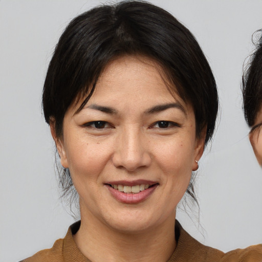 Joyful asian adult female with medium  brown hair and brown eyes