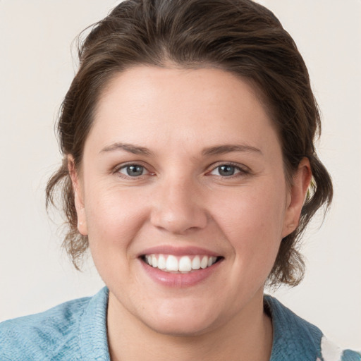 Joyful white young-adult female with medium  brown hair and grey eyes