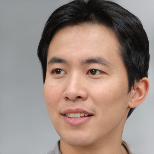 Joyful asian young-adult male with short  brown hair and brown eyes