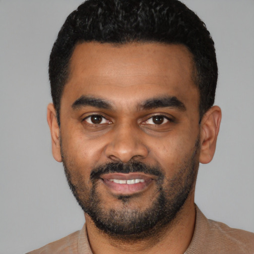Joyful black young-adult male with short  black hair and brown eyes