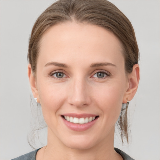 Joyful white young-adult female with medium  brown hair and grey eyes