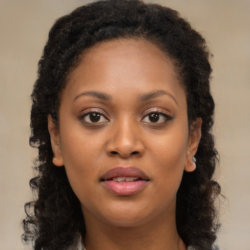 Joyful black young-adult female with long  brown hair and brown eyes