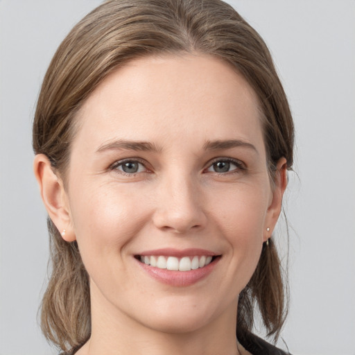 Joyful white young-adult female with medium  brown hair and grey eyes