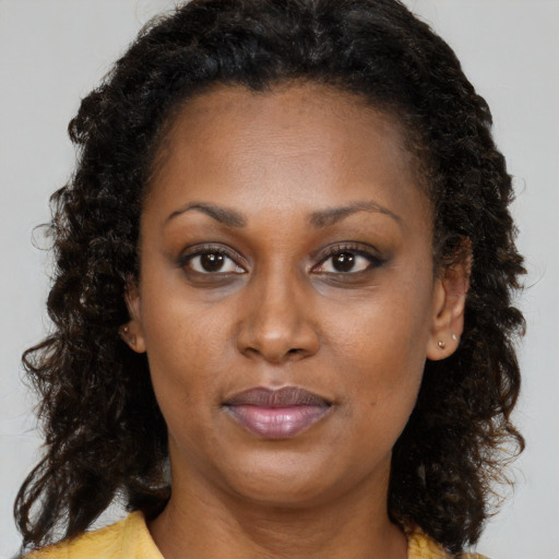 Joyful black adult female with long  brown hair and brown eyes