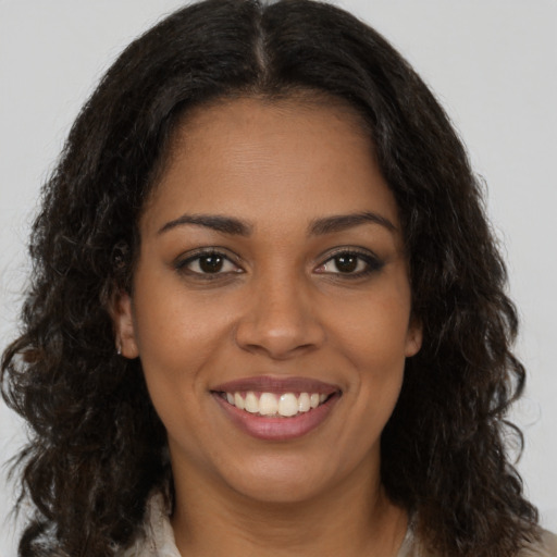 Joyful black young-adult female with long  brown hair and brown eyes