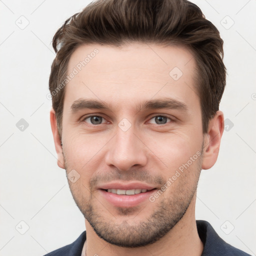 Joyful white young-adult male with short  brown hair and grey eyes