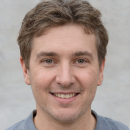 Joyful white young-adult male with short  brown hair and grey eyes