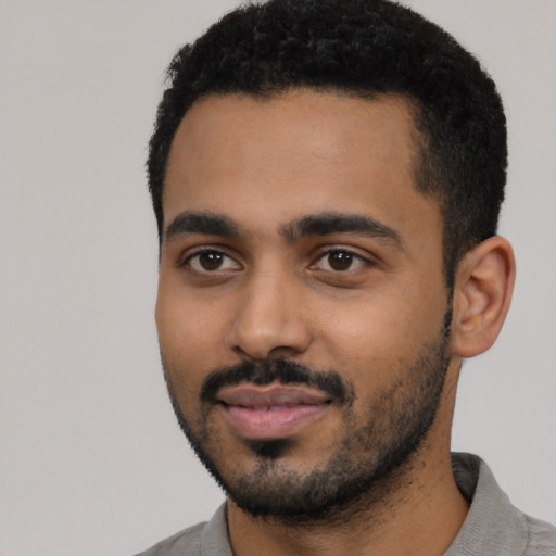 Joyful black young-adult male with short  black hair and brown eyes