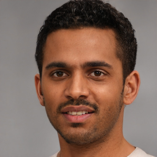 Joyful black young-adult male with short  black hair and brown eyes