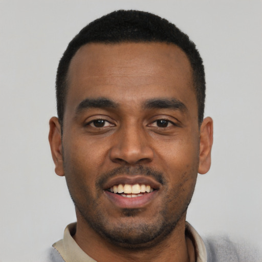 Joyful black young-adult male with short  black hair and brown eyes