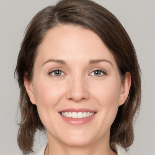 Joyful white young-adult female with medium  brown hair and grey eyes